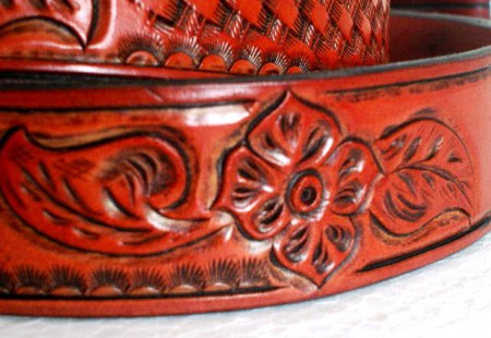 Kožený opasek zdobený basketem a vyřězávaný malým motivem květiny. Třikrát barvený a dvakrát lakovaný.